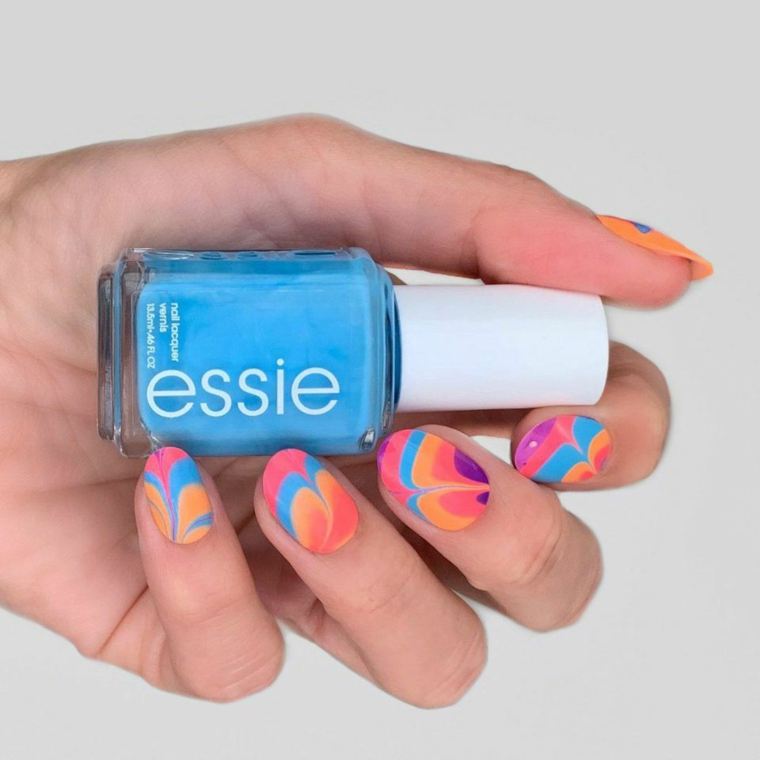 Bottiglietta smalto Essie, unghie colorate ad onde, colate estive, mano di una donna